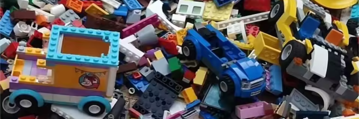 Collection of building brick toys of all colors with some cars in the center. Big pile.