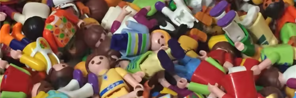 A collection of play figures together in a bin of all colors and sizes with accessories.