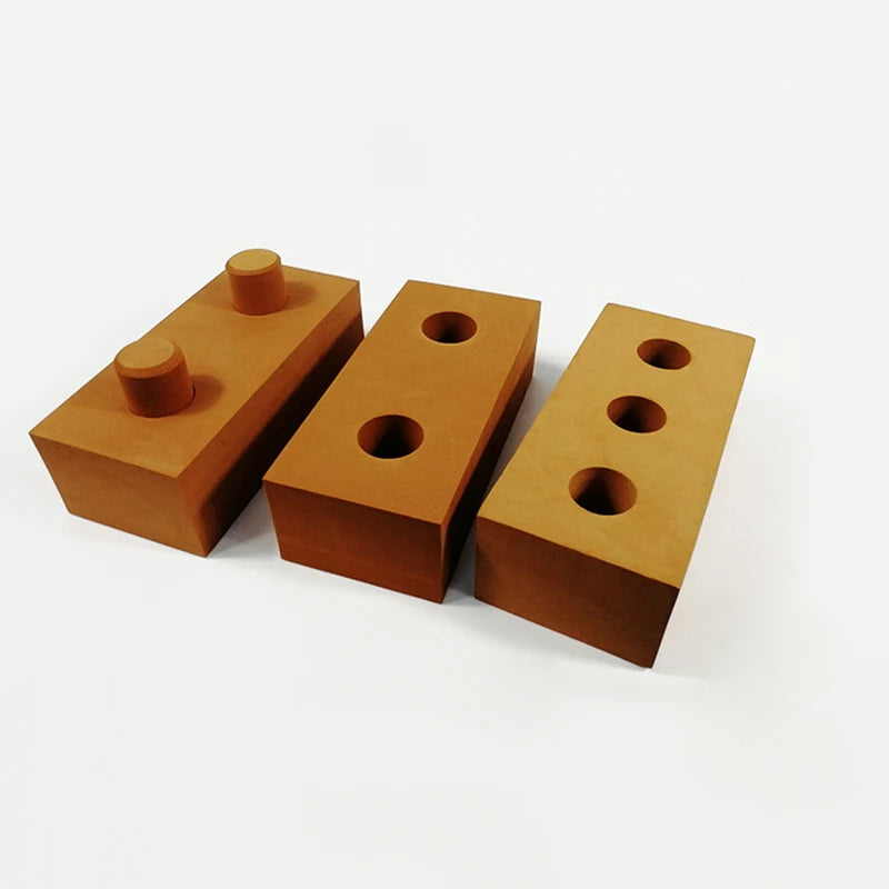 Three brown building blocks with cylindrical protrusions on a white background