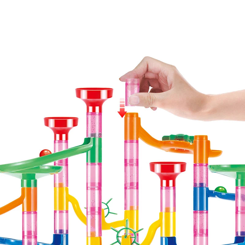 Colorful marble run toy set with a hand placing a marble on it against a white background
