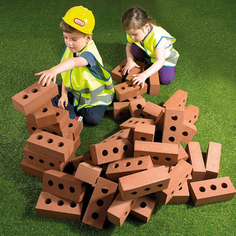 Two children playing with toy bricks on a green surface