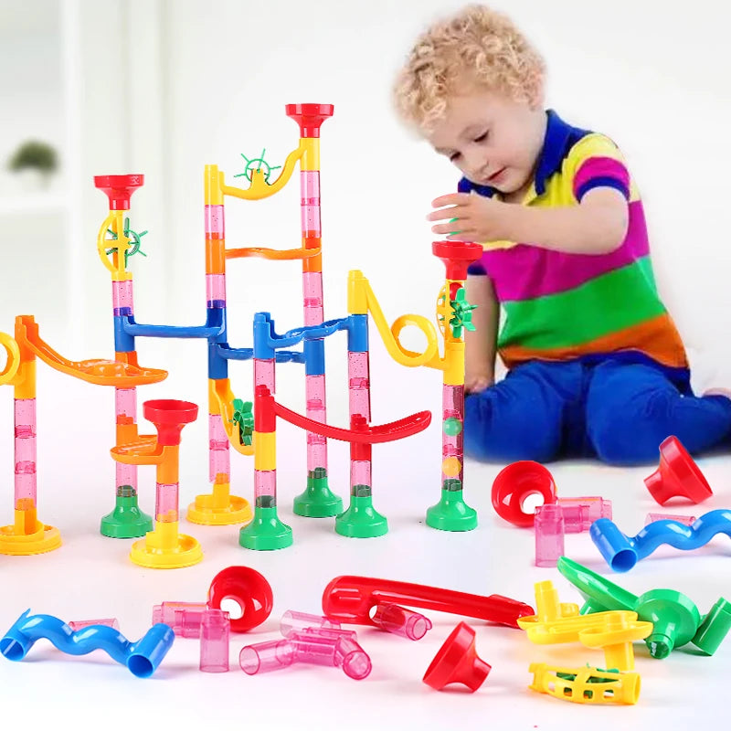 Child playing with a colorful marble run toy set on a white background