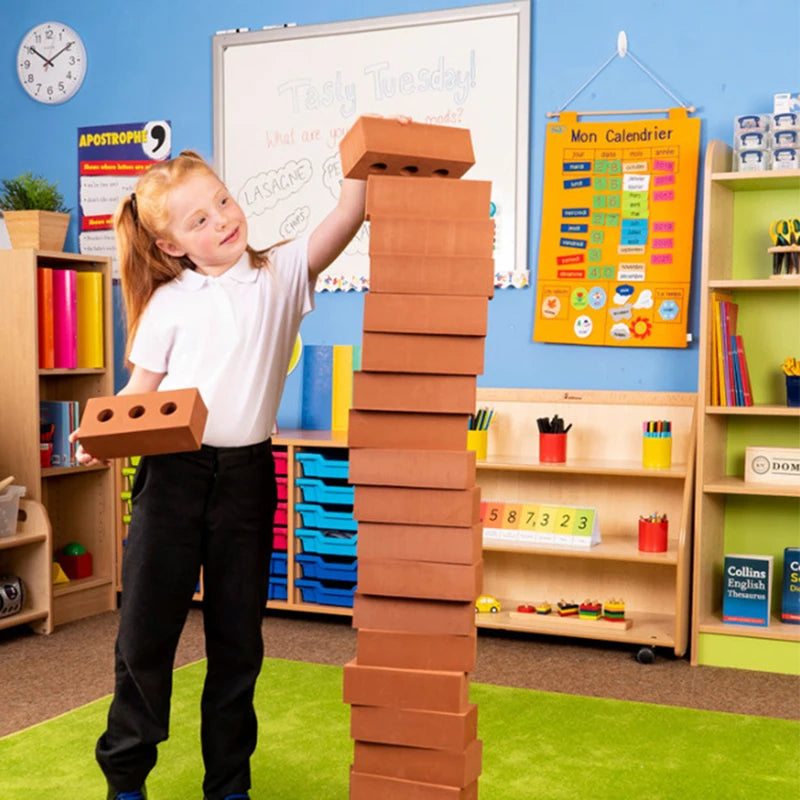 Child building a tower with cardboard blocks in a classroom setting