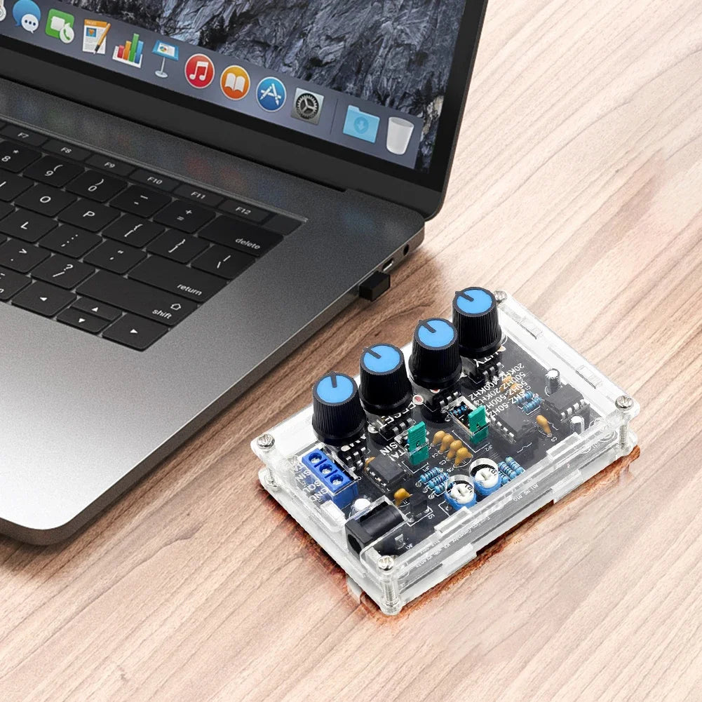 Electronic circuit board with knobs next to a laptop on a wooden surface