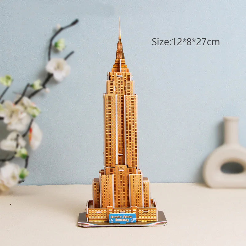 Model of the Empire State Building on a table with a light blue wall and vase in the background