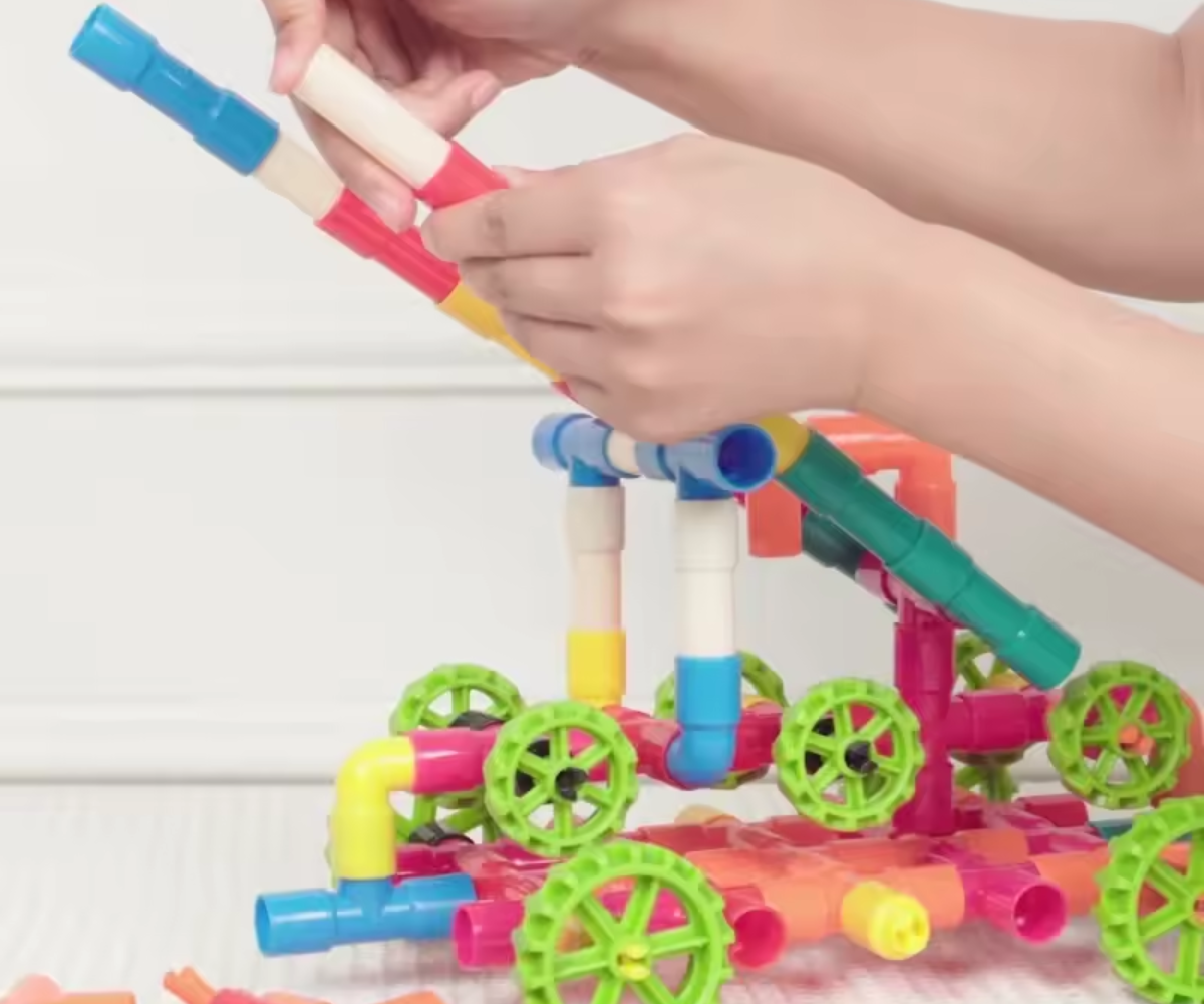 Colorful toy construction set with wheels being assembled by a child's hands.